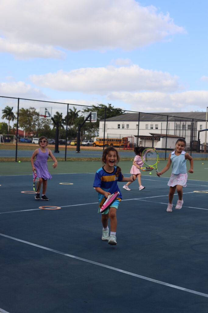 Smiling girl playing at tennis academy for kids in Doral